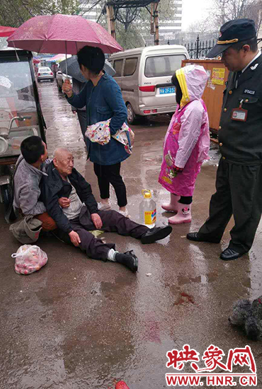 女孩為倒地老人撐傘。