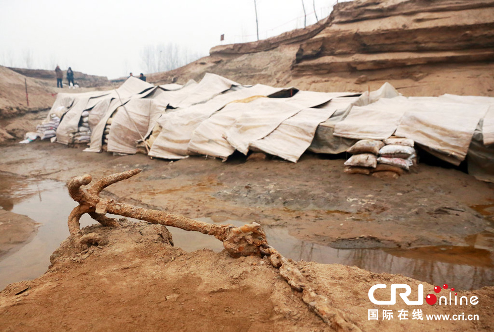 2014年1月6日，河南洛陽古沉船發(fā)掘現(xiàn)場，古沉船鐵錨從見天日，靜靜地躺在古船旁。