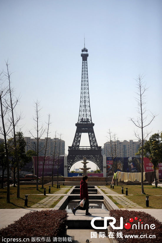 　2014年3月21日，杭州天都城，農(nóng)民在山寨埃菲爾鐵塔下耕作。圖片來源：東方IC