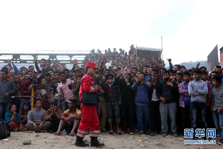 圍觀的尼泊爾民眾在中國國際救援隊(duì)成功搜救出幸存者后向搜救隊(duì)員歡呼致意。