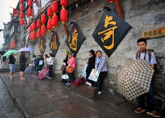 　4月29日上午11時(shí)20分，一些游客和古城當(dāng)?shù)氐木用穸阍谝粋€(gè)酒吧的屋檐下避雨。這些當(dāng)?shù)鼐用褚詾橛慰团恼罩\生，一場(chǎng)降雨讓他們的生意更加清淡。