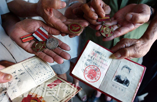 幾位志愿軍老兵展示自己的立功證、傷殘軍人證與勛章