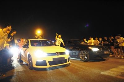 8月24日晚，東壩中街飆車現(xiàn)場，兩輛車并排等待出發(fā)指令，旁邊許多愛好者前來觀看比賽。新京報(bào)記者