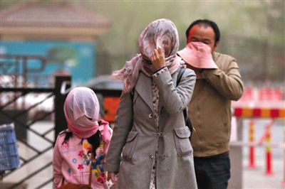 昨日下午，朝陽區(qū)豆各莊，行人將紗巾裹在頭上防沙塵。