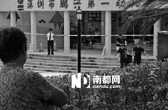 →7月19日，鵬興花園第一幼兒園門前，民警在現(xiàn)場進(jìn)行完勘查取證后，園長和保安的尸體被運(yùn)走。南都記者 徐文閣 攝