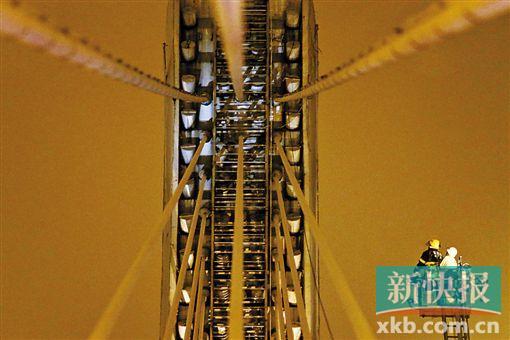 截至今日零時，男子仍未有下橋舉動。圖為公安和消防人員乘消防云梯在高空上和男子交談。