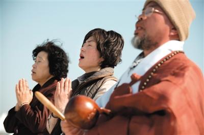 23日，一名僧侶引領人們?yōu)樗勒咂矶\。