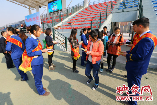 活動現場工作人員給同學們發(fā)放宣傳冊、環(huán)保袋。