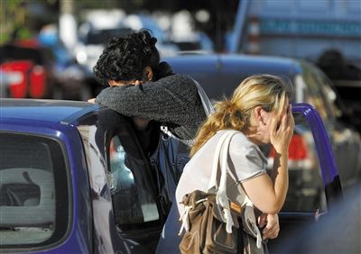 27日，遇難者親友在火災(zāi)現(xiàn)場旁哭泣。