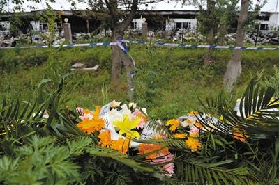 昨日，吉林省德惠市吉林寶源豐禽業(yè)有限公司燃燒事故現(xiàn)場警戒線外，遇難者家屬在路邊擺放了花圈祭奠逝去的親人。吳江 攝