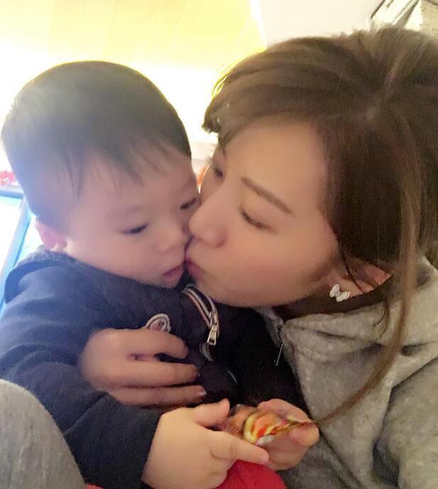 照片中李念狂吻兒子，小寶貝自顧自地玩著。