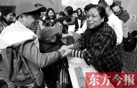 昨日，鄭大四附院的大樓前，“面人鄭”鄭玉芬（右）向前來捐款的殘疾人表示感謝