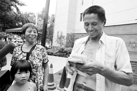 昨日，鄭州市明達路與豐慶路交叉口西300米路南，來自中牟的瓜農(nóng)拿到西瓜款，笑開顏東方今報記者袁曉強