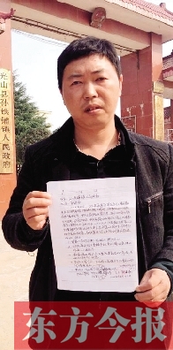 吳大強(qiáng)手持還款協(xié)議在鎮(zhèn)政府門前