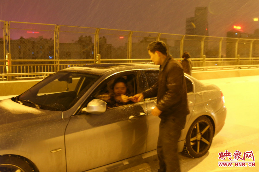 “推車人”幫助一輛車上坡后，收取“勞務(wù)費”。