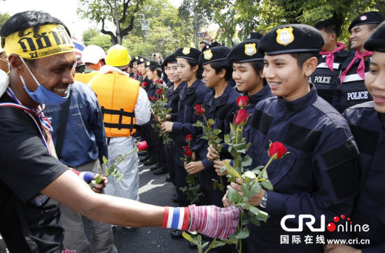 2013年12月03日,曼谷總理府與曼谷警署允許反政府示威民眾進入,雙方進入暫時“停戰(zhàn)”狀態(tài)迎接泰王生日。曼谷警察總署,女警們手持鮮花送給反政府示威民眾。圖片來源:Manish Swarup/東方IC