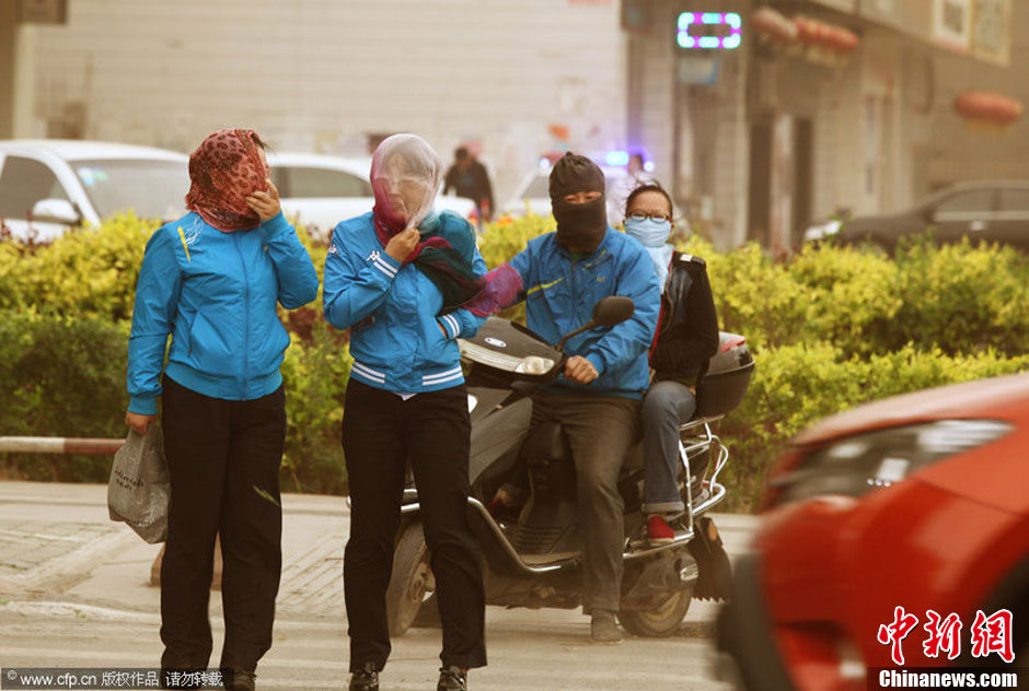 2014年04月23日，新疆維吾爾自治區(qū)吐魯番地區(qū)，市民戴著口罩行走在大風(fēng)沙塵中的吐魯番市街頭。