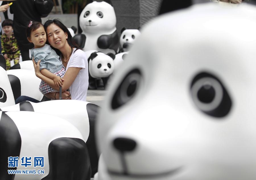 6月2日，一位家長帶著孩子在上海街頭和大熊貓模型合影。