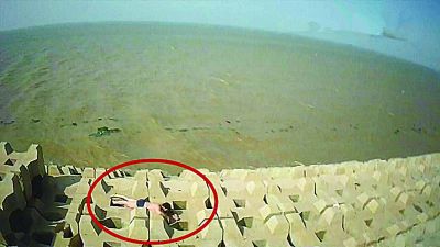 孫正龍游上岸，趴在海邊精疲力盡。