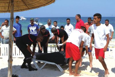 6月26日，在突尼斯蘇塞，救生員和醫(yī)務(wù)人員在發(fā)生襲擊事件的海灘運(yùn)送一名死者的遺體。新華社發(fā)