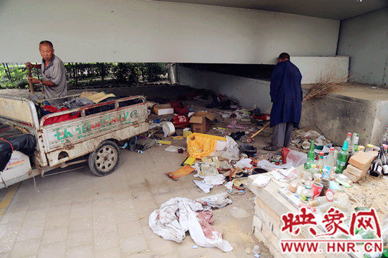 負(fù)責(zé)高架橋下綠化的人員在清理流浪漢留下的垃圾和雜物。