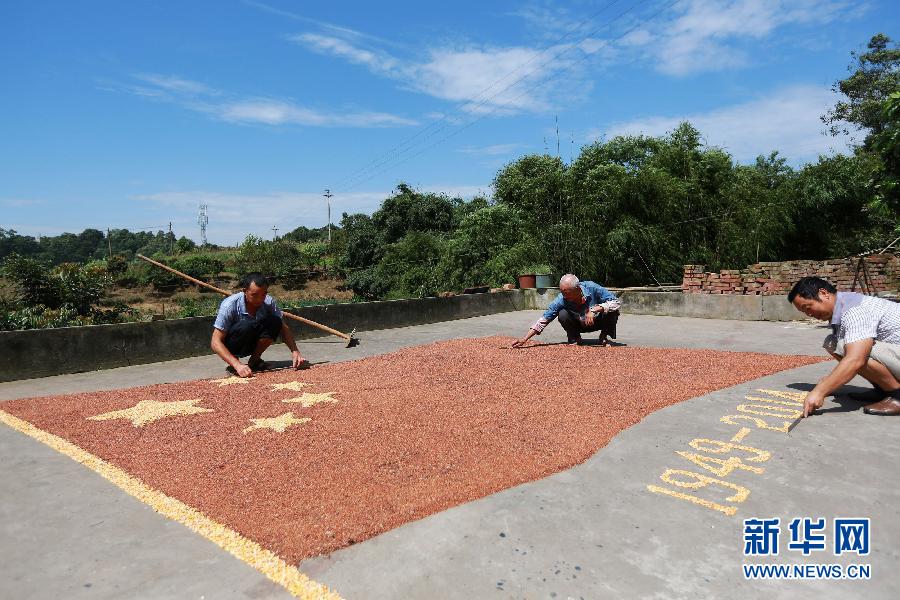 村民馬玉明（左一）用豐收的高粱和玉米在院壩里擺國旗為祖國慶生。