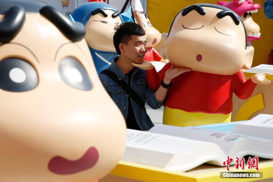 4月22日，游客與蠟筆小新合影?！跋灩P小新25周年紀(jì)念特展”日前在北京開展，吸引了不少市民游客。
