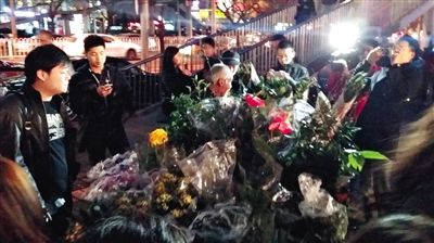 昨晚7時許，三里屯太古里西邊附近一過街天橋旁邊，聞訊而至的網(wǎng)友圍住了賣花老人，爭相買花。 網(wǎng)友“行者橙子”供圖